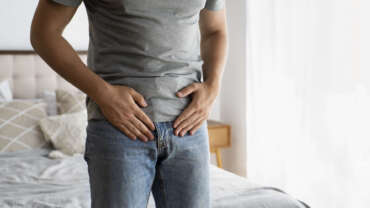 Man placing pressure just below abdomen, indicating pain