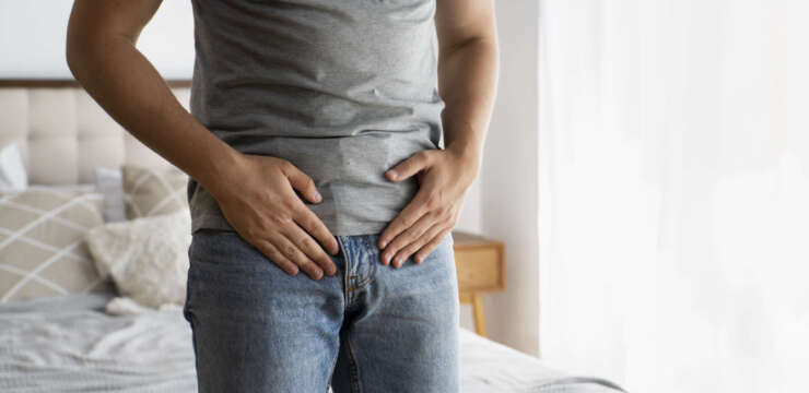 Man placing pressure just below abdomen, indicating pain