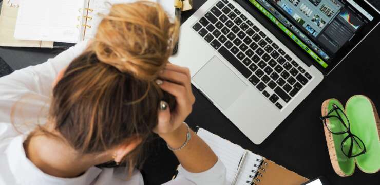 Woman at desk with head in hands, stress at work